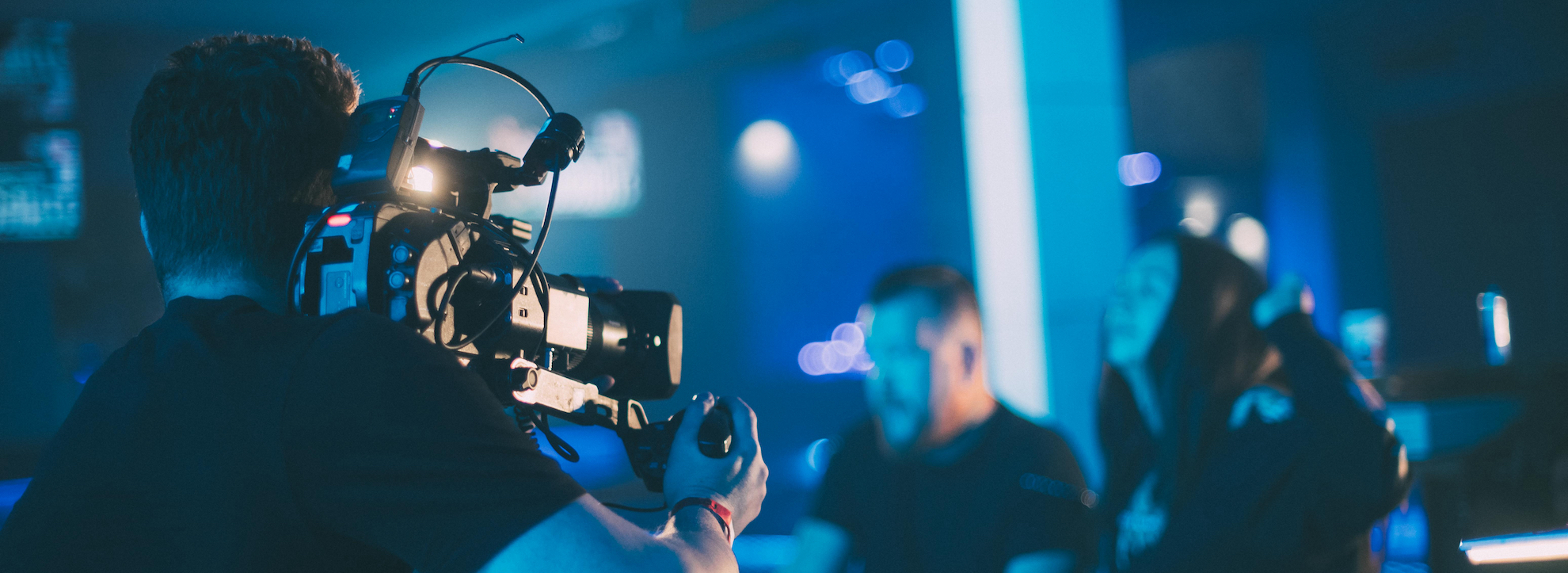 Director of photography with a camera in his hands on the set. Professional videographer at work on filming a movie, commercial or TV series. The filming process indoors, on a concert stage.